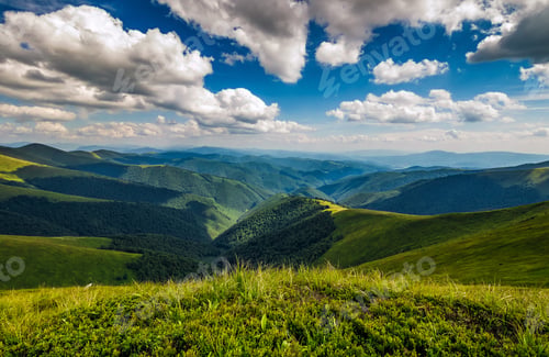 Preview: Green Grass On Hillside Meadow In High Mountains Under The Cloudy Blue Sky
