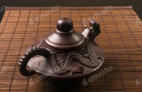 Preview: Brown Chinese Teapot Of Yixing Clay With Traditional Ornament On Bamboo Mat