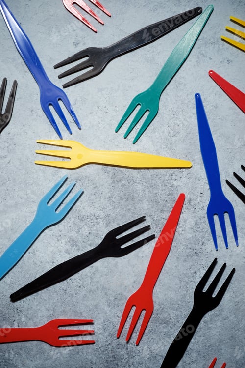 Preview: Multicolored Plastic Cutlery On A Stone Table.