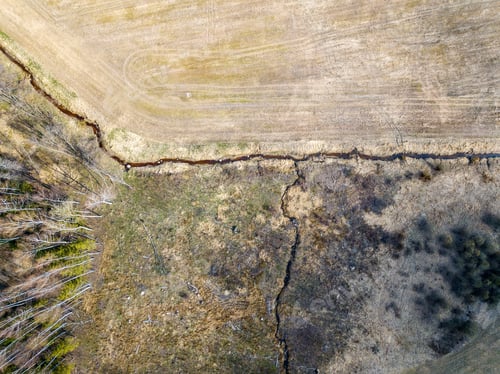 Preview: Aerial View Of Small Country River Bed Wavy In Spring Time In Countryside With Dry Grass And Some