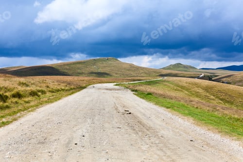 Preview: Landscape With Dirt Road In The Mountains Under Cloudy Sky