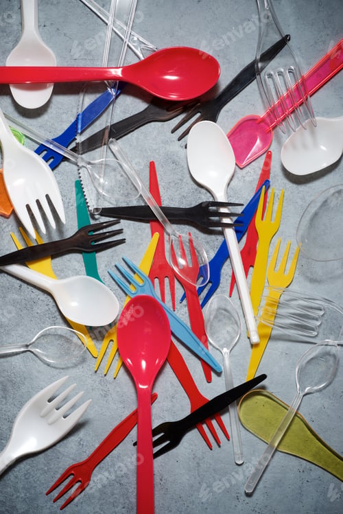 Preview: Multicolored Plastic Cutlery On A Stone Table.