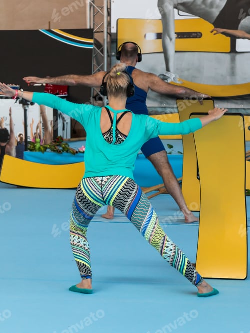 Preview: Blond Woman With Headphones Practicing A Pose With New Curved Board Concept: Flyboard