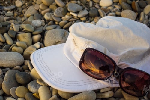 Preview: White Cap And Sunglasses On Pebble Beach, Sunset