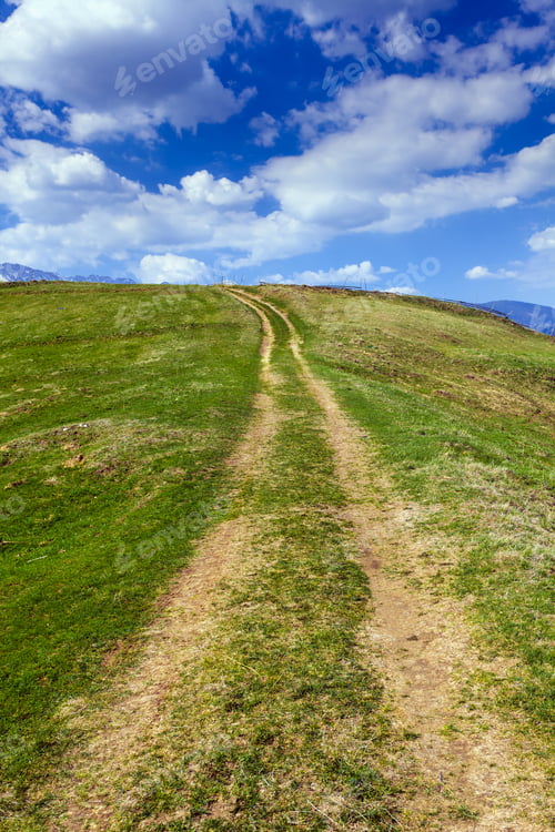 Preview: Landscape With A Rural Dirt Road In The Mountains Under Sky With Fluffy Clouds
