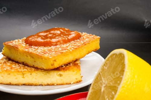 Preview: Slice Of Cheesecake With Sesame Seeds, Apricot Jam And Lemon Slices On A Black Background