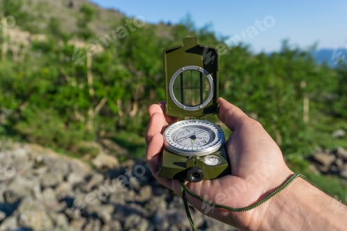 Preview: Compass In Hand Against A Background Of A Blurry Mountain Forest Landscape
