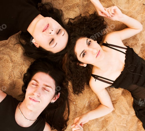 Preview: Two Girls And A Boy Laying On The Sand Hand In Hand