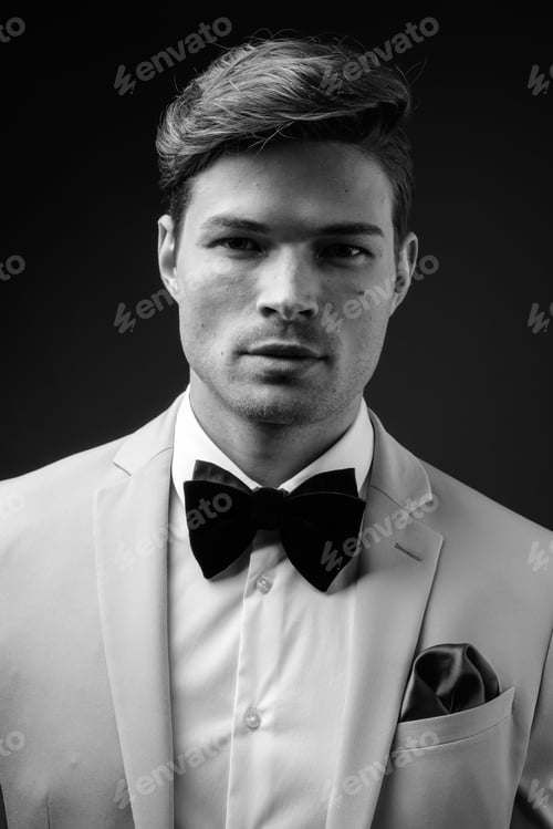 Preview: Studio Shot Of Young Handsome Businessman Wearing Suit Against Gray Background In Black And White