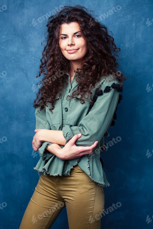 Preview: Young Pretty Woman With Curly Brunette Hair Posing Cheerful On Blue Background, Lifestyle People