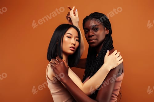 Preview: Young Pretty Asian And Afro Woman Posing Cheerful Together On Brown Background, Lifestyle Diverse