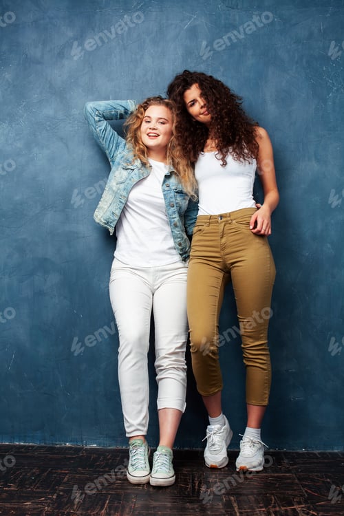 Preview: Young Pretty Teenage Girls Friends With Blond And Brunette Curly Hair Posing Cheerful On Blue
