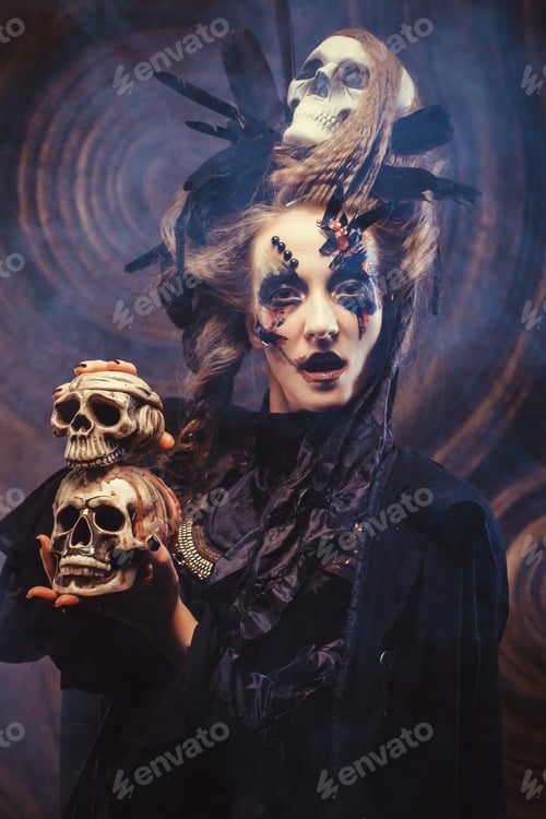 Preview: Young Witch Holding Skull. Bright Make Up And Smoke- Halloween Theme. Studio Shot.
