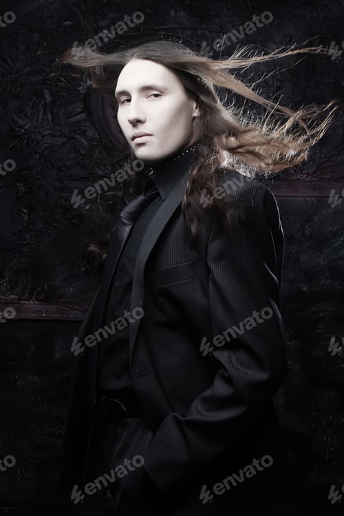 Preview: Portrait Of A Fashionable Male Model With Long Hair Over Dark Background. Studio Shot