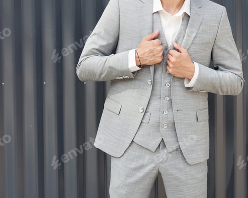 Preview: Part Of The Body. A Young Businessman In A Fashionable Gray Suit Posing Against A Gray Wall