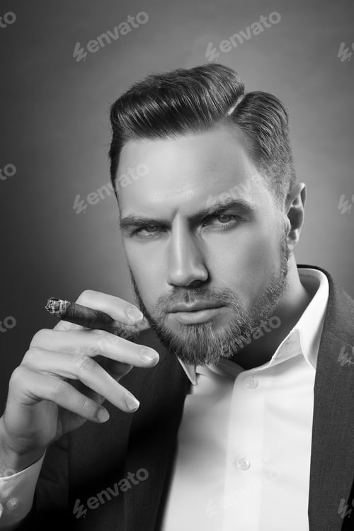 Preview: Young Handsome Bearded Caucasian Man Sitting On Chair With A Cigar. Perfect Skin And Hairstyle