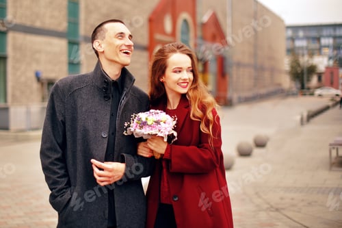 Preview: Young Romantic Couple, Beautiful Girl With Flowers Has Dating In The City. Man In Gray Overcoat And
