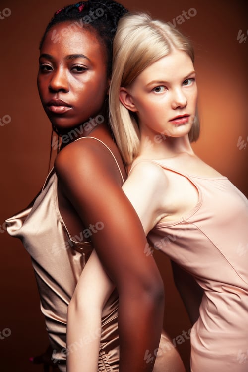 Preview: Two Pretty Girls African And Caucasian Blond Posing Cheerful Together On Brown Background