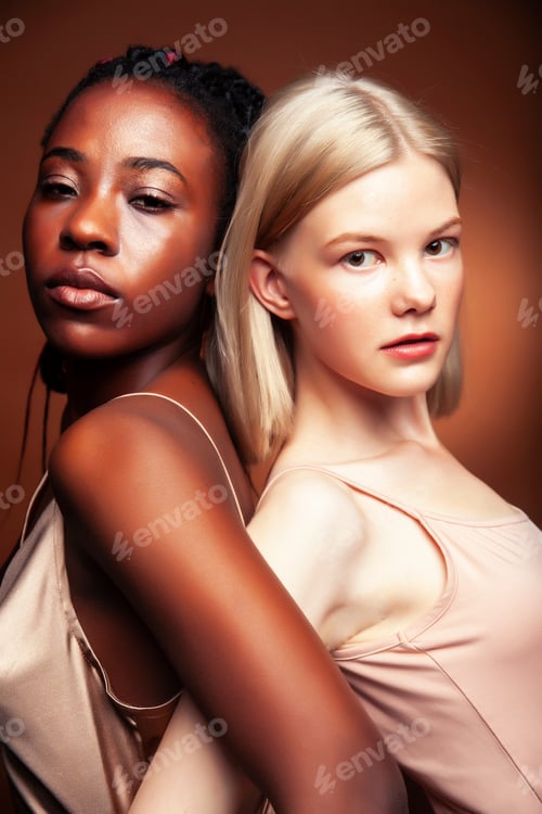 Preview: Two Pretty Girls African And Caucasian Blond Posing Cheerful Together On Brown Background