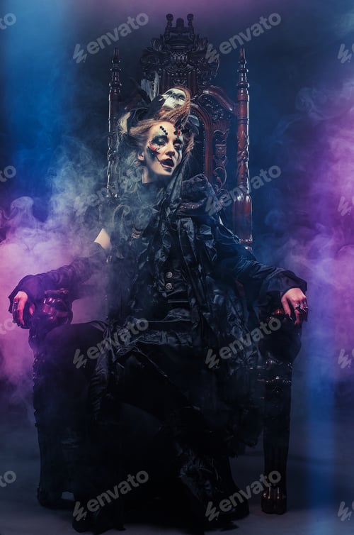 Preview: Young Beautiful Witch Sits On A Chair. Bright Make Up, Skull, Smoke- Halloween Theme.