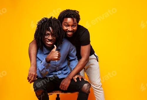 Preview: Two African American Guys Posing Cheerful Together On Yellow Background, Lifestyle People Concept