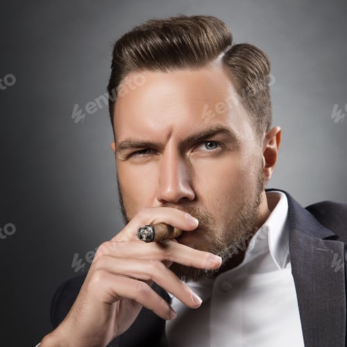 Preview: Young Handsome Bearded Caucasian Man Smoking A Cigar. Perfect Skin And Hairstyle. Wearing Grey Suit
