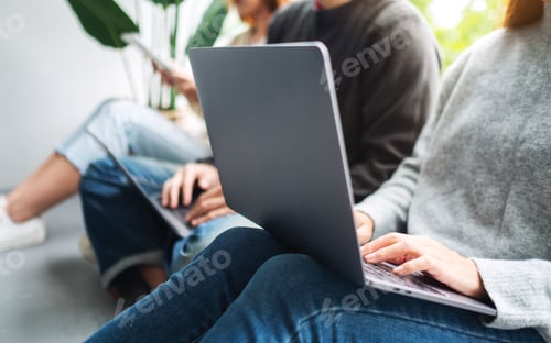 Preview: A Group Of Young People Sitting And Using Laptop Computer And Digital Tablet Together
