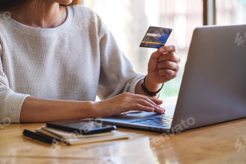 Preview: Closeup Image Of A Woman Holding Credit Cards While Using Laptop Computer In Office