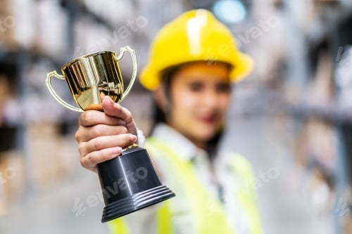 Preview: Happy Woman Warehouse Worker Holding A Trophy After Being Selected As An Outstanding Employee