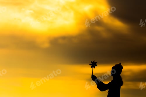 Preview: Silhouette Of Beautiful Girl Holding Wind Toy Or Wind Turbine Or Pinwheel And Wool Hat At Meadow On