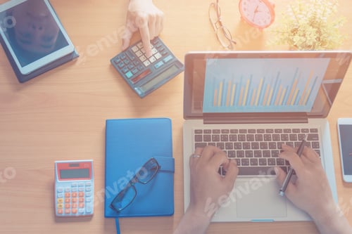 Preview: Business Man Working At Office With Laptop, Tablet And Graph Data Documents On His Desk.