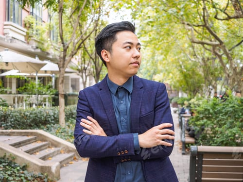 Preview: Portrait Of A Handsome Chinese Young Man In Blue Suit Looking Aside With Arms Crossed.