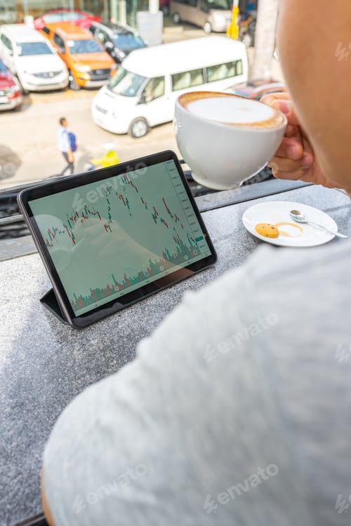 Preview: Rear View Of Freelancer Watching Stock Market Graph On Tablet
