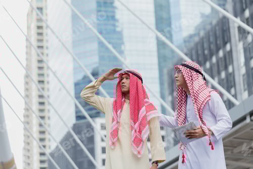 Preview: Two Arab Or Muslim Business Man Standing At Front Modern Office Discussing Work With Tablet. Ethnic