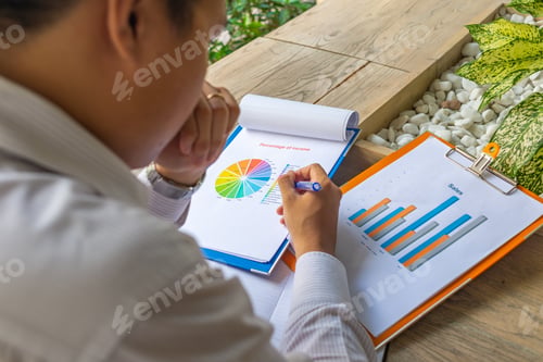 Preview: Asian Financial Executive Analyzing Data On Statistics Documents