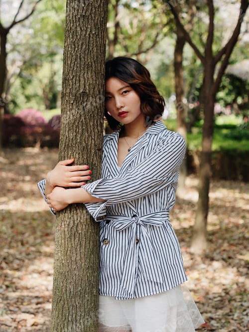 Preview: Portrait Of A Beautiful Chinese Girl Hugs A Tree And Looking At Camera Emotionally In A Sunny Day.