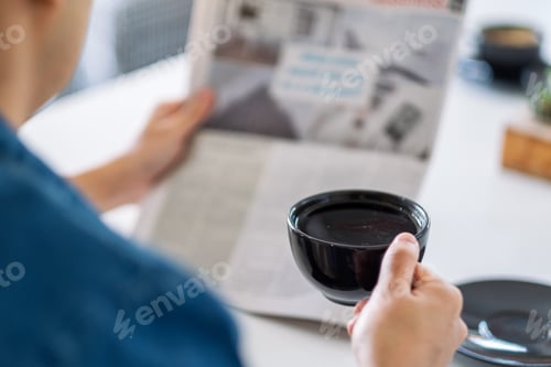 Preview: Closeup Image Of A Man Reading Newspaper And Drinking Coffee In The Morning