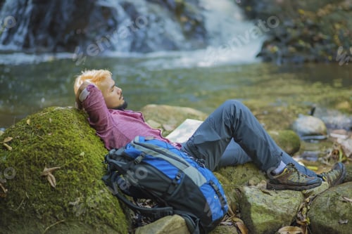 Preview: Young Tired Hiker With Backpack Sitting On The Rock In Forest While Resting After Active Walk