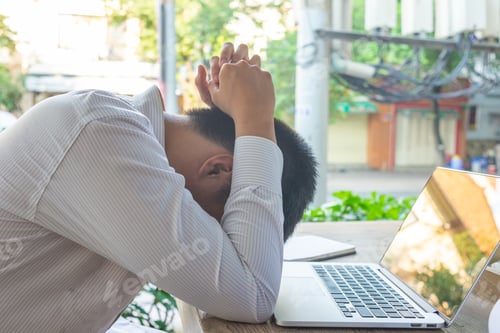 Preview: Frustrated Businessman Holding Head Sitting With Laptop At Outdoor Coffeeshop