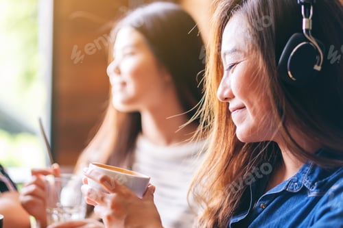 Preview: A Beautiful Asian Woman Enjoy Listening To Music With Headphone While Drinking Coffee With Friends