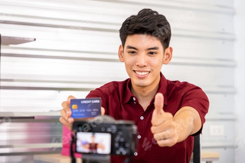 Vista previa: Joven bloguero comerciante en línea asiático que usa la cámara para grabar un vídeo en vivo para vender, con tarjeta de crédito