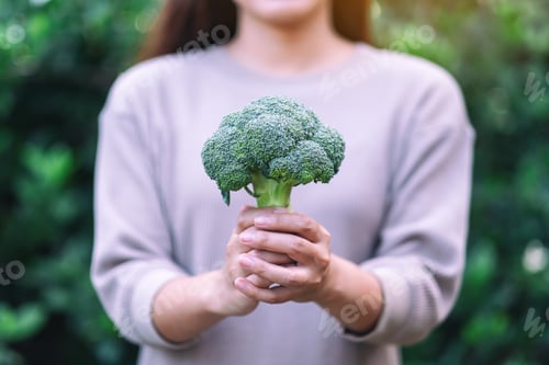 Preview: A Woman Holding And Giving A Green Broccoli In Hands