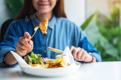 Preview: Closeup Image Of A Beautiful Asian Woman Eating Fish And Chips On Table In The Restaurant