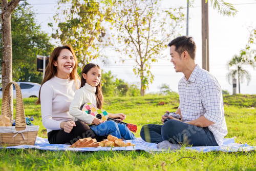 Preview: Happy Family Picnic. A Little Girl Playing Ukulele With Her Parents (Father, Mother) During