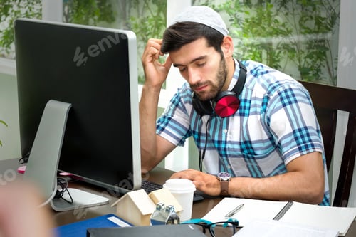 Preview: Muslim Handsome Bearded Guy Wearing A Taqiyah Cap Is Sitting At The Workplace And His Hand Touching