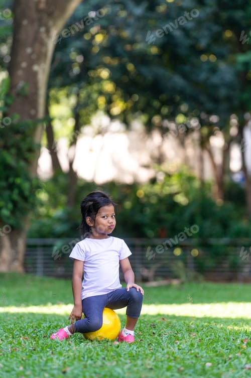 Vista previa: Cute Malay Girl With Her Football At The Park. Looking Away From The Camera