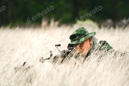 Preview: Soldier Lying On The Ground And Camouflage In Grass. Soldier Holding Gun Weapon And Waring Armor