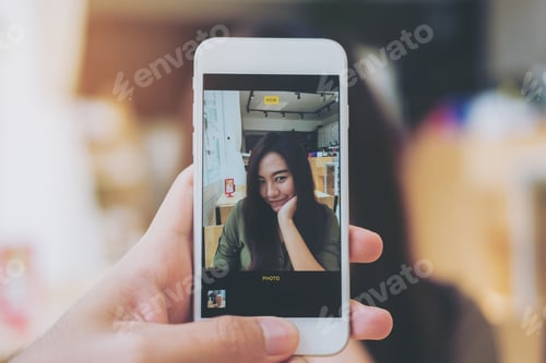 Preview: A Man Using White Smart Phone Taking A Picture Of A Beautiful Woman In Wooden Vintage Cafe