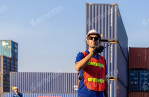 Preview: Engineer In Hardhat And Safety Vest Holding Two-Way Radio, Factory Worker Team At Cargo Container