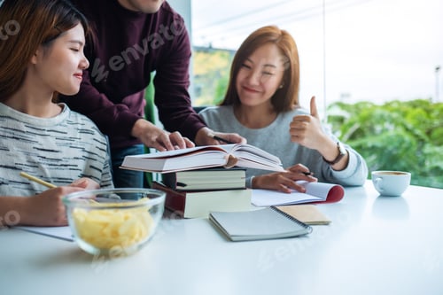 Preview: Group Of Young Students Tutoring And Catching Up Workbook Together